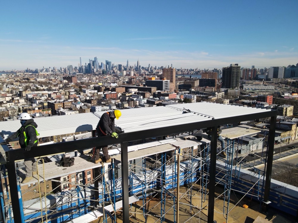 Breslow crew installing louver panels on rooftop steel frame with NYC skyline
