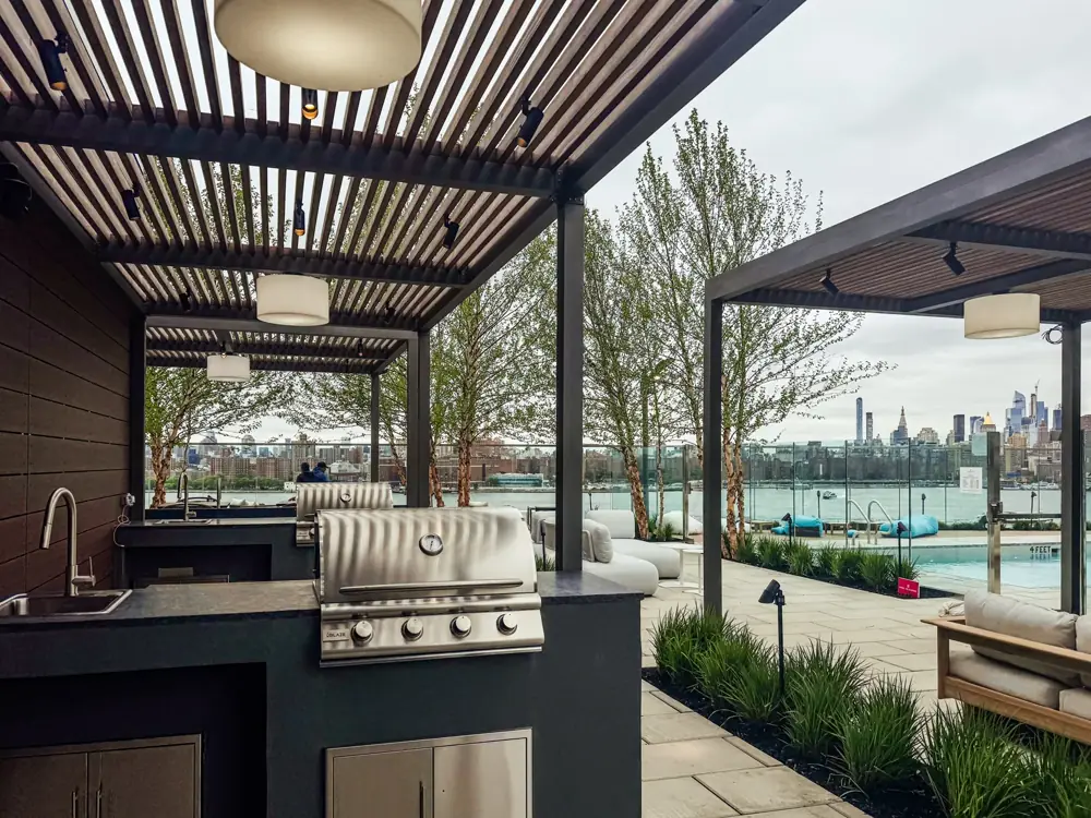 Rooftop outdoor kitchen with louvered pergola and city skyline